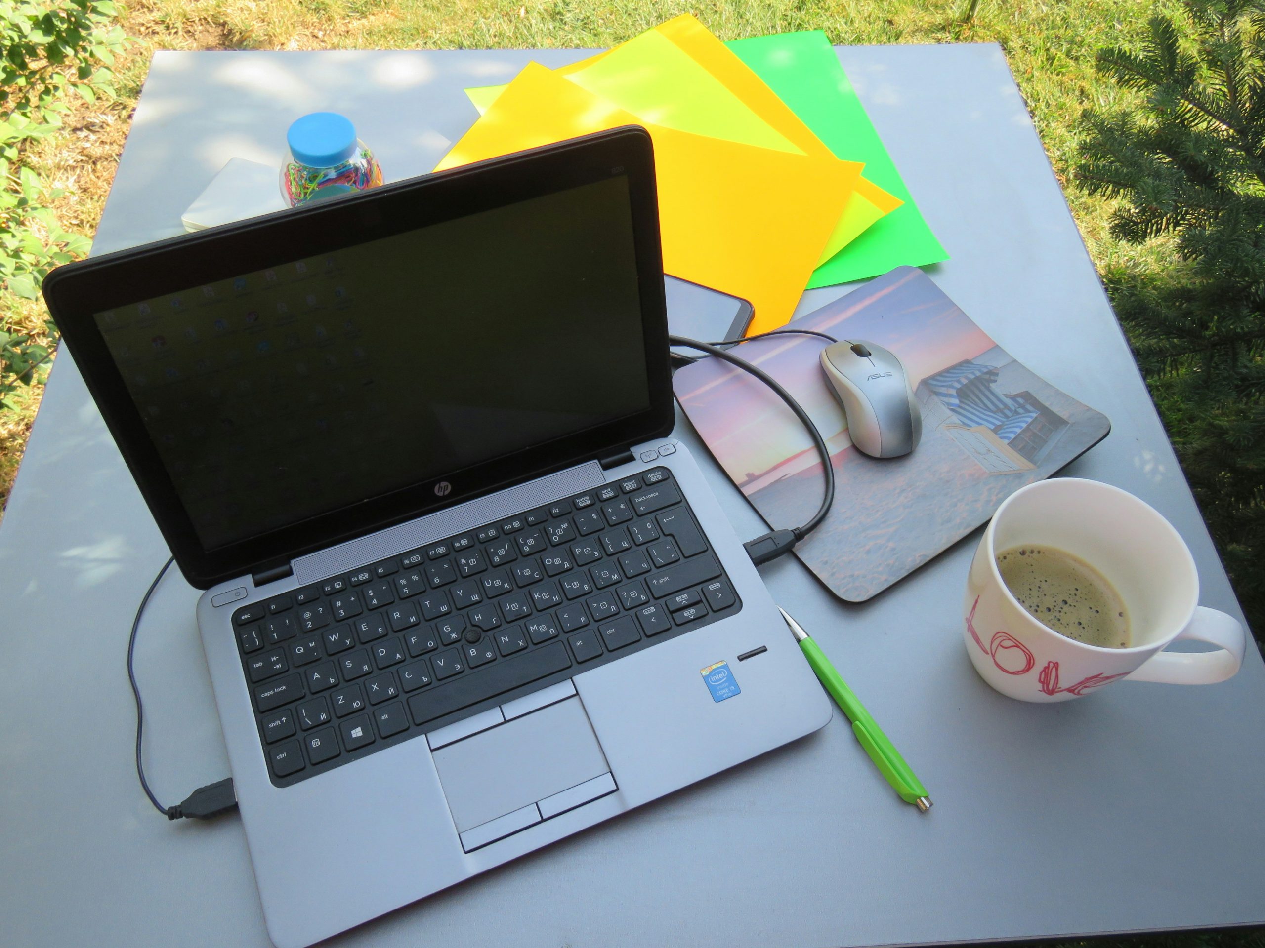 Top view of a desk with laptop displaying graphs, coffee cup, and energy saving plans blueprints