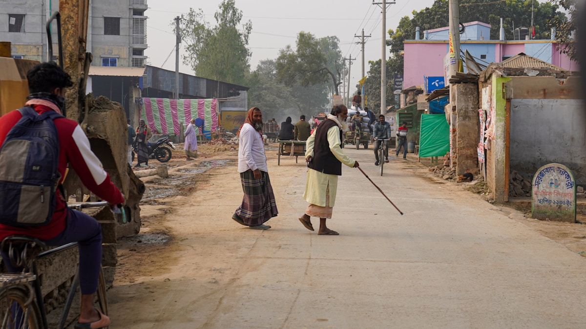 People walking on a dusty street in a village.