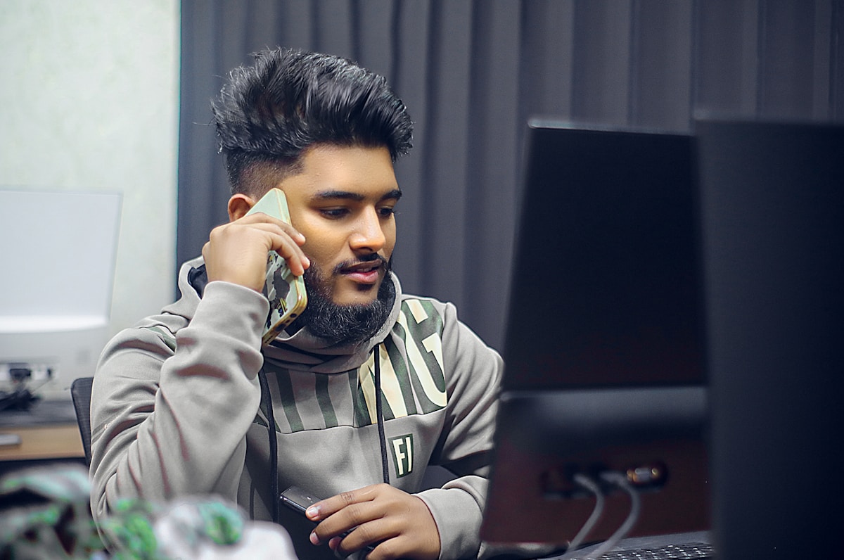 Man is on the phone in front of computer.