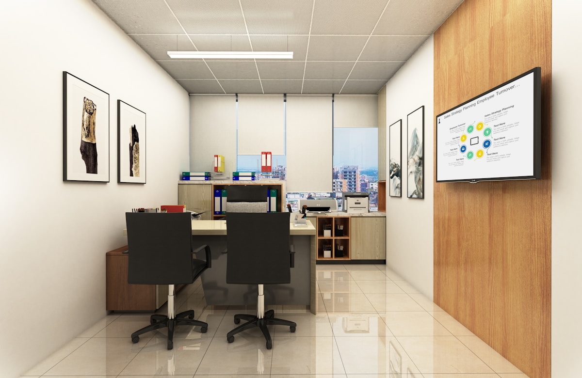 Modern office with desks, chairs, and a presentation screen.