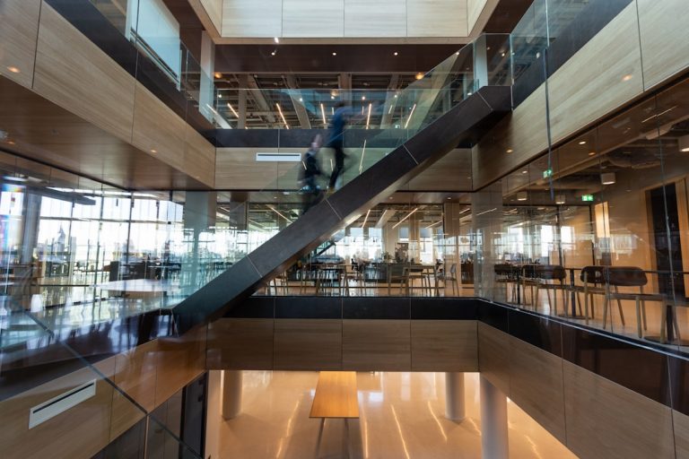 Un homme en veste noire marche sur un sol en bois brun avec un logiciel ERP bâtiment CEE pour gérer ses projets de constructi