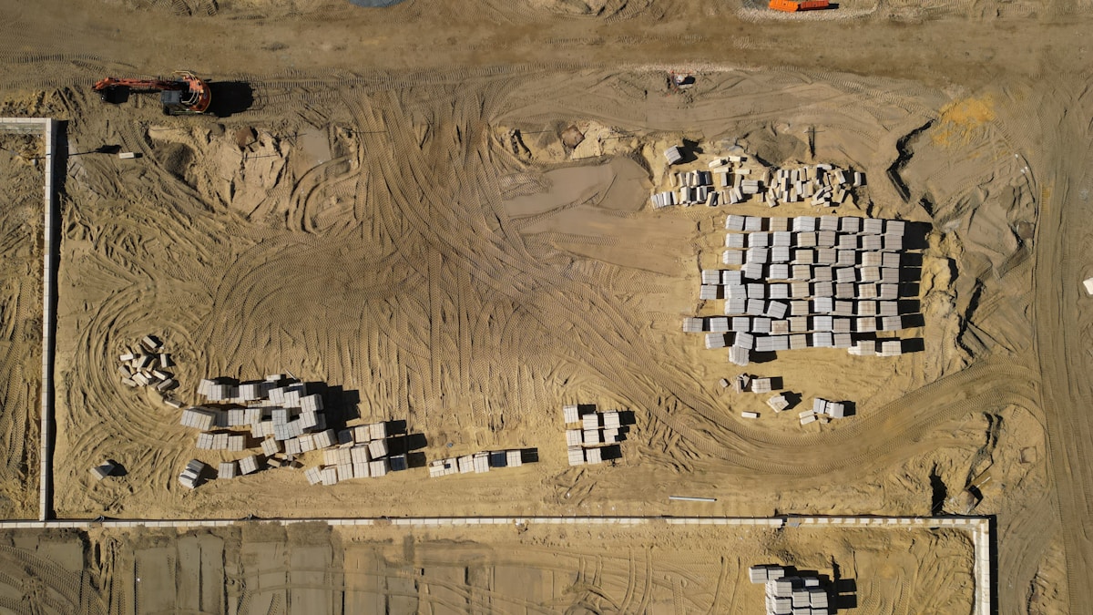 Chantier de construction avec des matériaux empilés et des engins de terrassement.