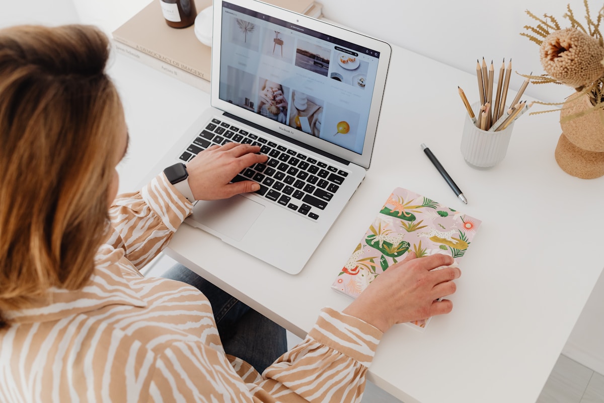 Femme travaillant sur un ordinateur portable avec un motif floral à côté.