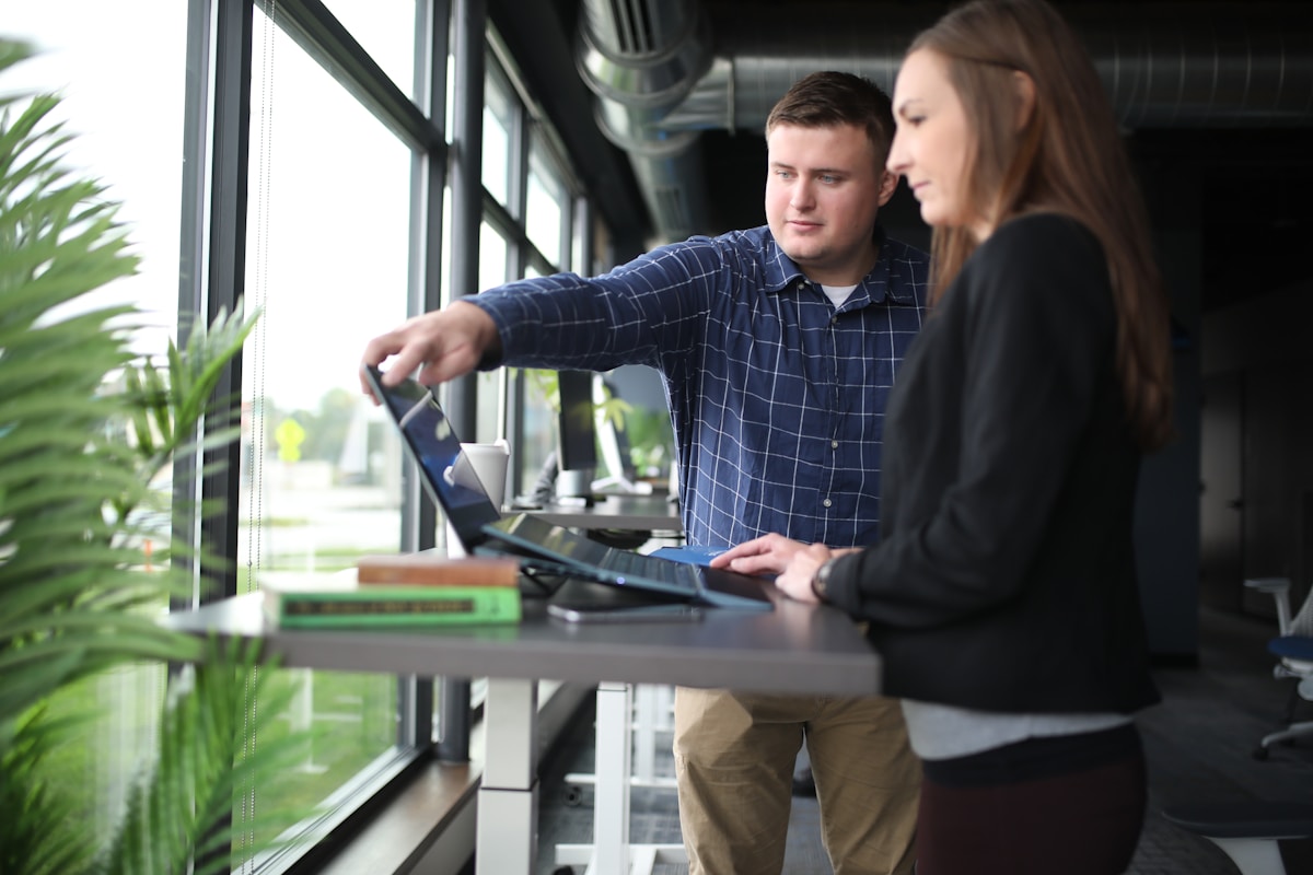 Deux personnes travaillant ensemble sur un ordinateur portable dans un bureau moderne.
