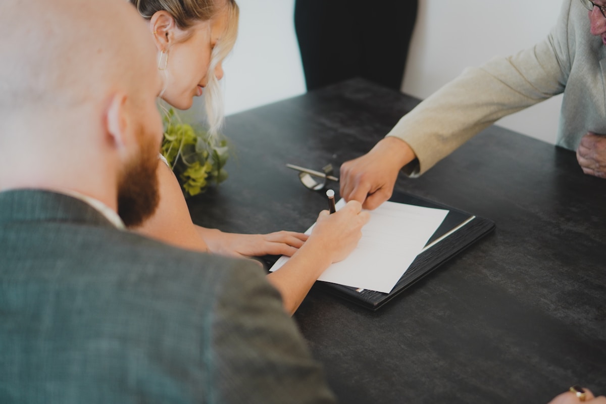 Deux personnes signant un document sur un bureau noir.