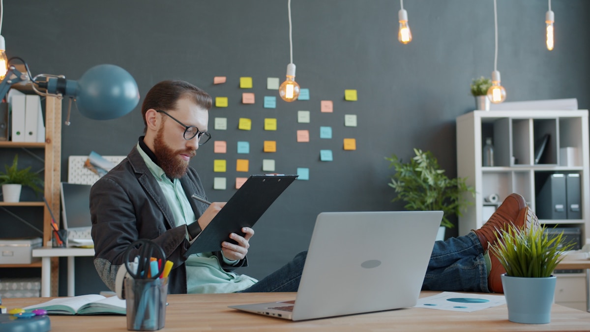 Un homme travaillant à son bureau avec un ordinateur portable et des notes.
