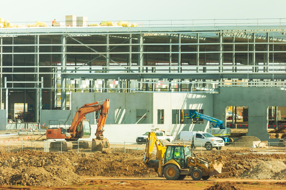 Chantier de construction avec engins de terrassement et structure en acier.