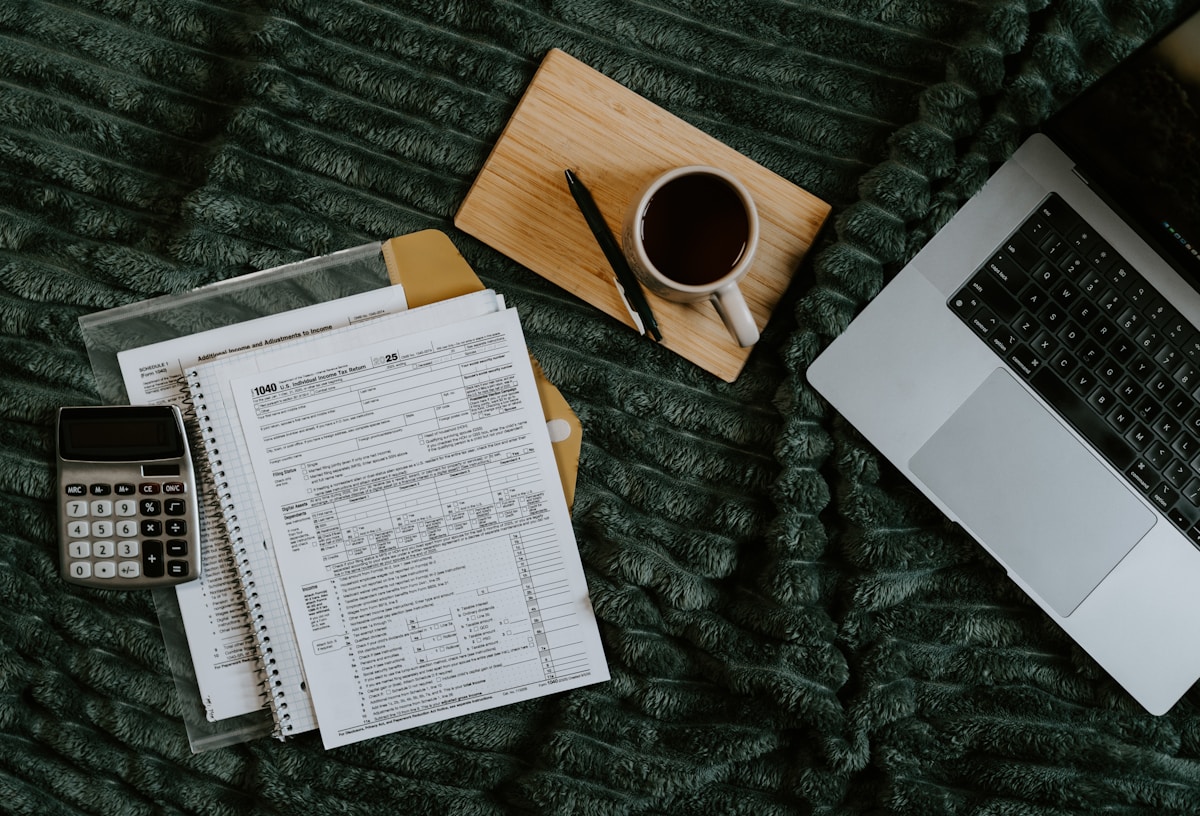 Bureau de travail avec documents fiscaux, ordinateur portable et tasse de café.