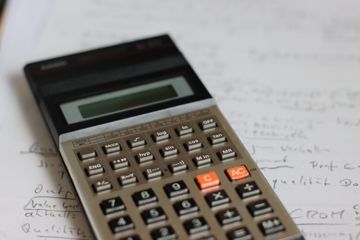 Calculatrice électronique avec boutons et écran LCD sur un bureau avec des notes manuscrites.
