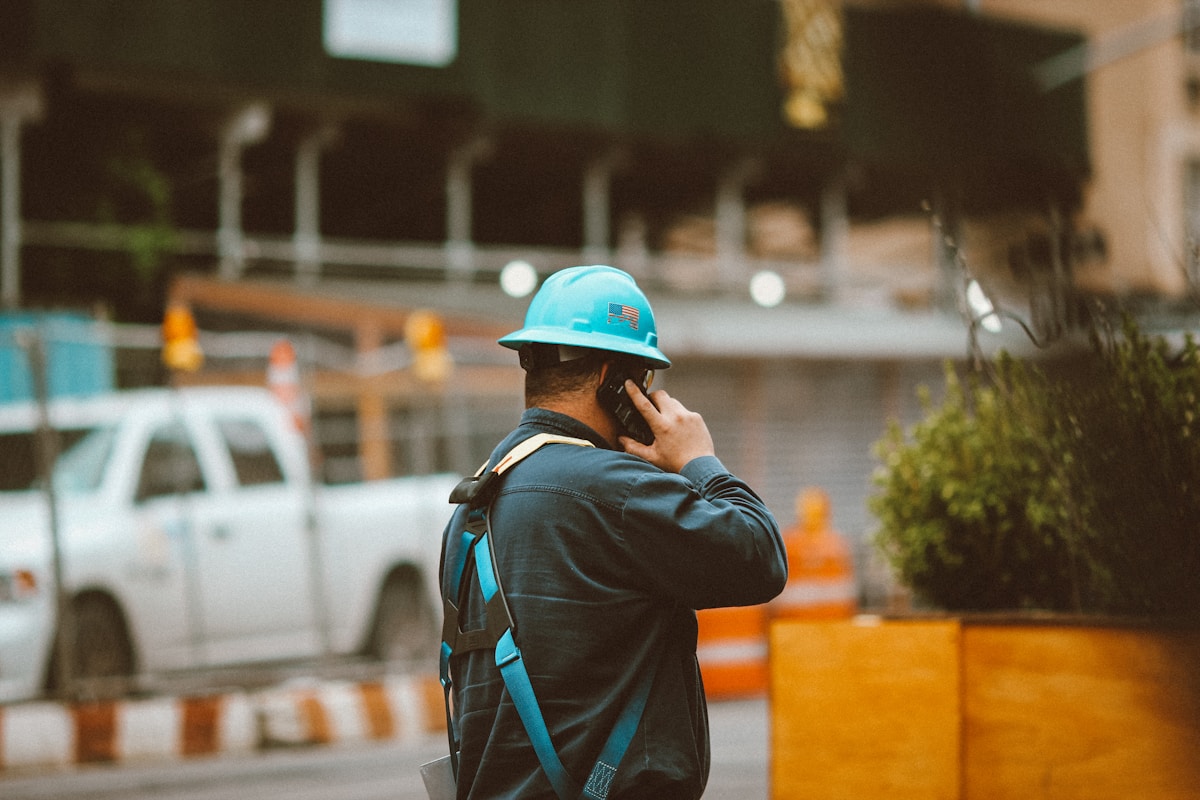 Ouvrier en uniforme bleu parlant au téléphone sur un chantier.