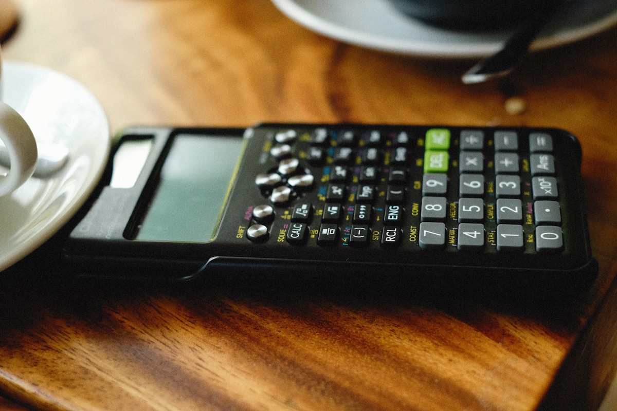Calculatrice scientifique noire avec touches multicolores sur une surface en bois.