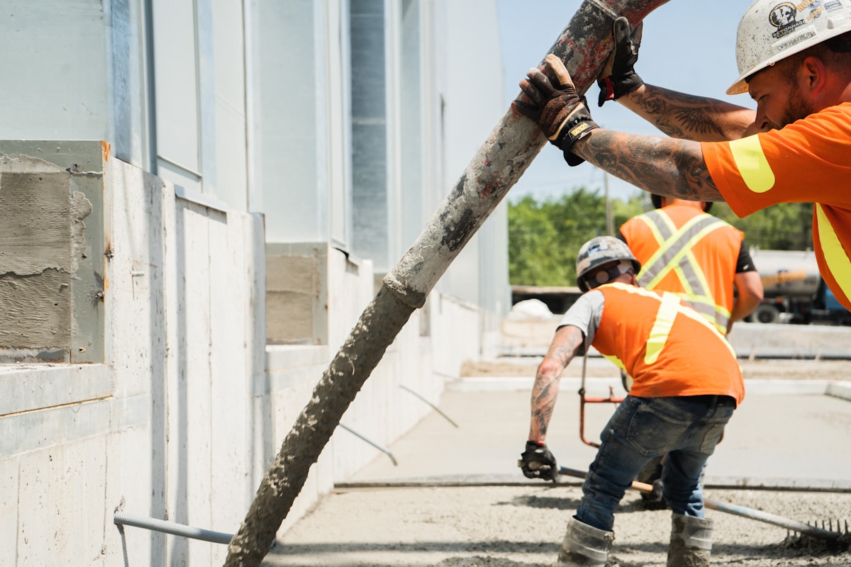 Ouvriers en équipement de sécurité coulant du béton sur un chantier de construction.